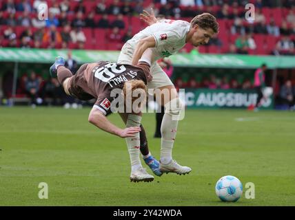 Augsburg, Deutschland. September 2024. Robert Wagner (L) von St. Pauli streitet mit Kristijan Jakic von Augsburg während des ersten Bundesliga-Fußballspiels zwischen Augsburg und St. Pauli in Augsburg am 15. September 2024. Quelle: Philippe Ruiz/Xinhua/Alamy Live News Stockfoto