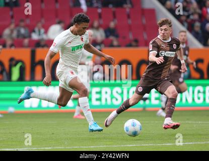 Augsburg, Deutschland. September 2024. Henri Koudossou (L) von Augsburg streitet mit Philipp Treu von St. Pauli beim Fußball-Spiel der ersten Bundesliga zwischen Augsburg und St. Pauli in Augsburg am 15. September 2024. Quelle: Philippe Ruiz/Xinhua/Alamy Live News Stockfoto