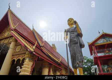 Außenansicht mit stehender Buddha-Statue mit Gehstock, Personal am Wat Chanthaboury buddhistischen Tempel in Vientiane, Laos. Stockfoto