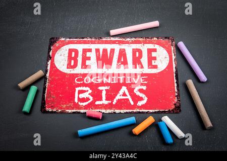 Kognitive Bias. Achtung: Schild mit Text und farbigen Kreideflächen auf dunklem Tafel-Hintergrund. Stockfoto