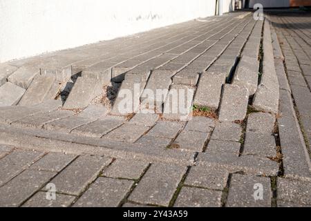 Aufgelöste und unebene Pflaster auf dem Bürgersteig. Stockfoto