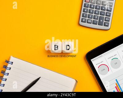 Geschäftsentwicklungskonzept. Das Akronym BD Business Development auf Holzwürfeln über gelbem Bürotischhintergrund. Stockfoto