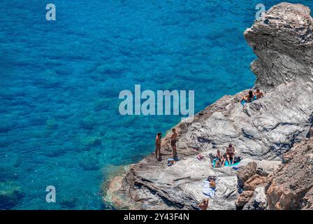 Schwimmer im Meer und auf den Klippen am anderen Ende des Mouros Strandes, einem fantastischen Kiesstrand auf Amorgos Insel, Kykladen, Griechenland Stockfoto