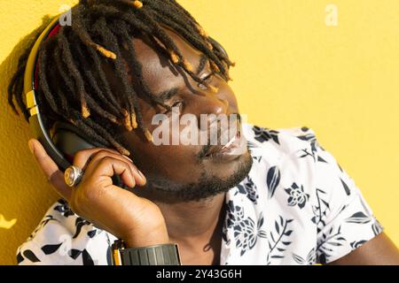 Junger afrikanischer Mann, der Musik mit Kopfhörern genießt Stockfoto