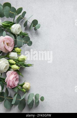 Eine wunderschöne Auswahl an rosa, weißen und cremefarbenen Blüten ist kunstvoll mit Eukalyptusblättern angeordnet, was eine elegante Komposition schafft, die perfekt für flo ist Stockfoto