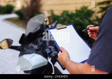 Hand hält das Clipboard, Hand hält den Stift auf weißem Papier auf Motorrad Hintergrund Stockfoto