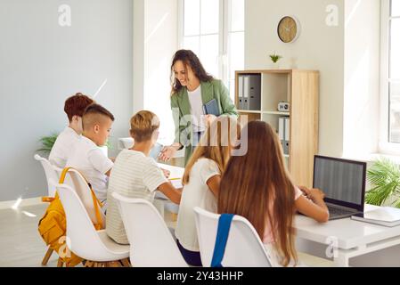 Schullehrer und Schüler lernen im Klassenzimmer, Schüler am Schreibtisch schauen auf ihren Laptop. Stockfoto