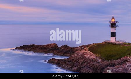 Ein Foto von einem Sonnenuntergang im 16:9-Format am Leuchtturm „Faro Illa Pancha“, der sich auf der Insel Pancha in der Nähe der Stadt Ribadeo in Galicien befindet; Stockfoto