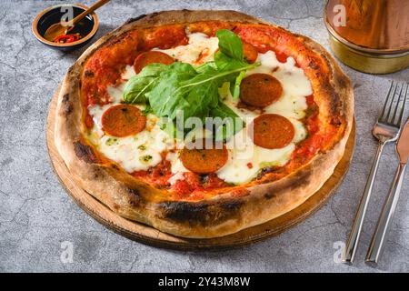 Blick von oben auf die neapolitanische Pizza mit Wurst, Jalapeno Paprika und Rucola Stockfoto