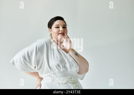 Eine atemberaubende Braut in Übergröße zeigt ihre Eleganz mit einem weißen Hochzeitskleid und funkelnden Ohrringen. Stockfoto
