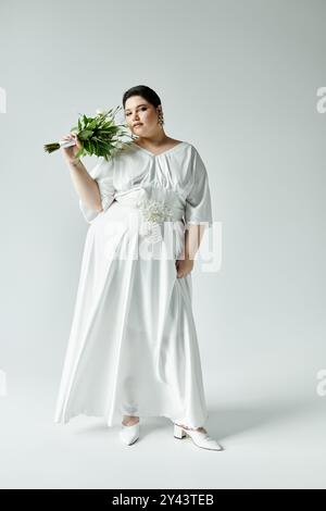 Eine atemberaubende Braut posiert elegant in einem weißen Hochzeitskleid mit einem Blumenstrauß und strahlendem Braut-Charme. Stockfoto