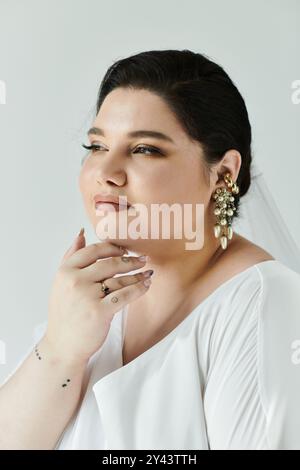 Eine schöne junge Braut strahlt Freude aus in ihrem fließenden Kleid und funkelnden Ohrringen, die Eleganz ausstrahlen. Stockfoto