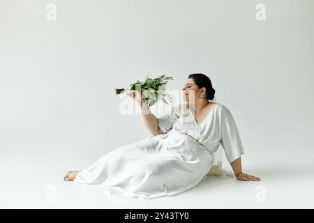 Eine wunderschöne Braut zeigt ihren strahlenden Stil in einem fließenden Kleid und Ohrringen und hält einen Blumenstrauß anmutig. Stockfoto