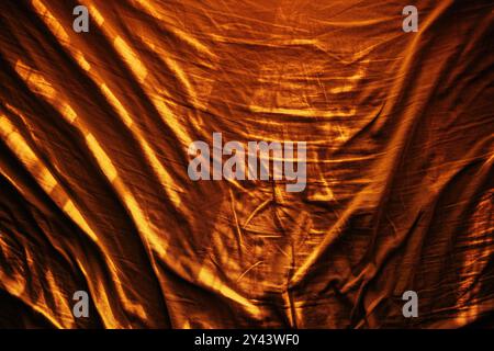 Zerknitterte und zerknitterte Bettlaken in warmem Orange von oben als abstrakte Textur und Hintergrund, Draufsicht Stockfoto