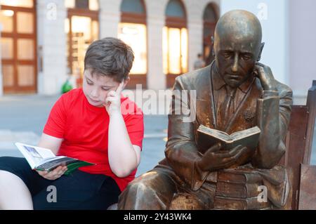 Italien, Friaul Julisch Venetien, Triest, Boy Reading neben einer Gabriele d'Annunzio Statue von Alessandro Verdi aus dem Jahr 2019 Stockfoto