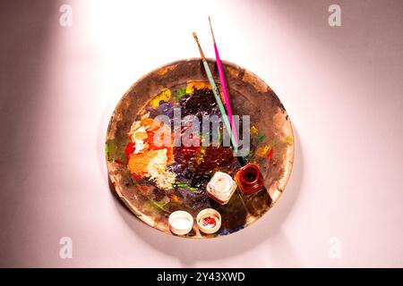 Eine Draufsicht auf die Zeichnung und Malerei eines Künstlers mit einer lebendigen Farbpalette mit zwei Farbflaschen und zwei Pinseln Stockfoto