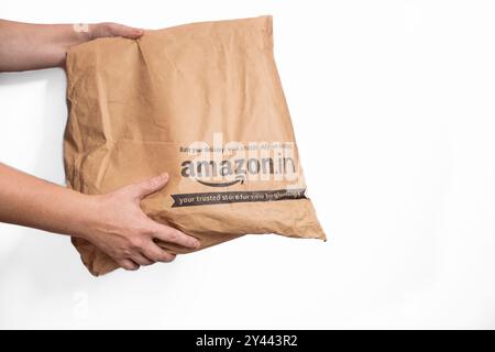 Paketpaket mit Eigenlieferung von Amazon Indien. Amazon.in Etikett Verpackungsbeutel isoliert auf weißem Hintergrund. Weibliche Hände erhalten einen Amazon bo Stockfoto