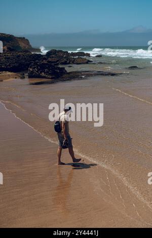 Ein Mann läuft entlang und leert den Strand in den Cascais. Stockfoto