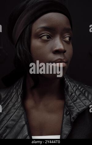 Junge schwarze Frau Porträt draußen. Sie trägt eine schwarze Jacke Stockfoto
