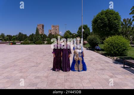 Drei Frauen in lila und blauen Kostümen stehen vor einem Gebäude Stockfoto