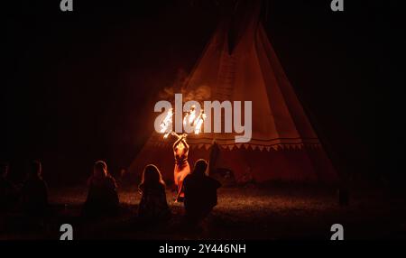 Eine bezaubernde Feuertänzerin zeigt ihr Talent während einer Vorstellung mit faszinierenden Flammen. Stockfoto