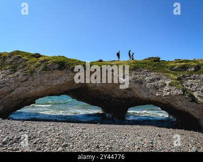 Menschen, die über natürliche Felsbögen am Strand in Neufundland spazieren. Stockfoto