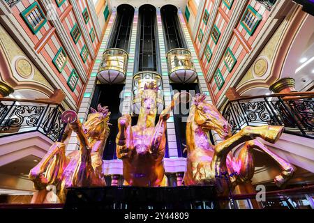 Asiatisches Kreuzfahrtschiff farbenfrohes Atrium, Treppen, Lobby, Innenraum, goldene Pferde, die eine Statue aufziehen, Panoramablick-Glasaufzüge, Star Cruises Superstar Virgo Stockfoto