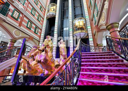 Asiatisches Kreuzfahrtschiff farbenfrohes Atrium, Treppen, Lobby, Innenraum, goldene Pferde, die eine Statue aufziehen, Panoramablick-Glasaufzüge, Star Cruises Superstar Virgo Stockfoto