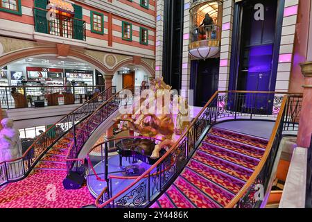 Asiatisches Kreuzfahrtschiff farbenfrohes Atrium, Treppen, Lobby, Innenraum, goldene Pferde, die eine Statue aufziehen, Panoramablick-Glasaufzüge, Star Cruises Superstar Virgo Stockfoto