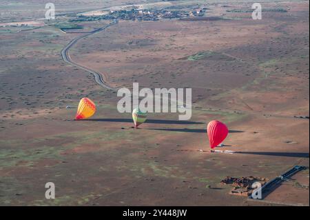 Drei Heißluftballons, die gerade in den ländlichen Randbezirken von Marrakesch, Marokko, gelandet sind. Die bunten Ballons beginnen zu entlüften. Luftaufnahme Stockfoto