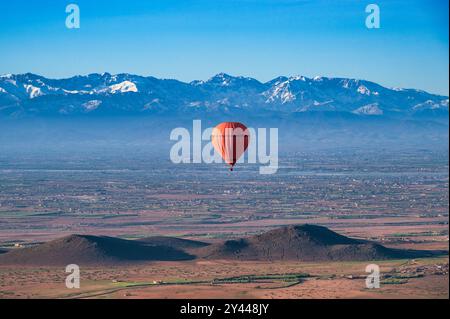 Ein roter Heißluftballon, der an einem klaren Frühlingstag in der Nähe von Marrakesch, Marokko, über die Wüste schwingt Stockfoto