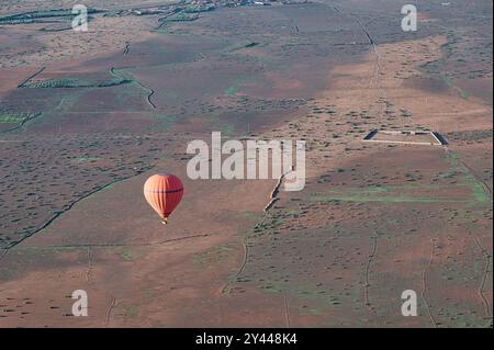 Ein roter Heißluftballon, der an einem klaren Frühlingstag in der Nähe von Marrakesch, Marokko, über die Wüste schwingt Stockfoto