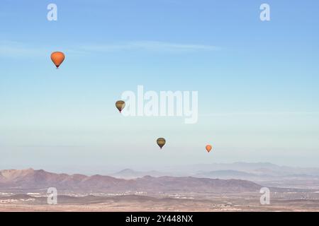 Mehrere Heißluftballons fliegen früh an einem Frühlingsmorgen über die Wüste Agafay in der Nähe von Marrakesch, Marokko. Stockfoto