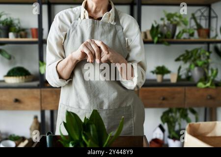 Eine reife Frau kümmert sich liebevoll um ihre Pflanzen in einem einladenden Atelierraum. Stockfoto