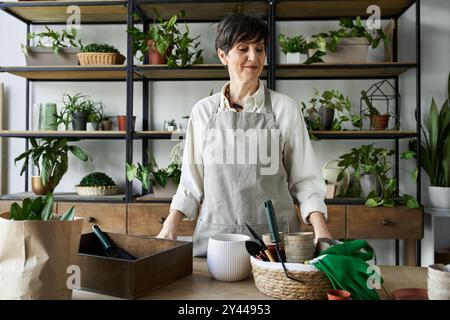 Ein Gärtner pflegt liebevoll ihre Pflanzen in einem gemütlichen, üppigen Studio. Stockfoto