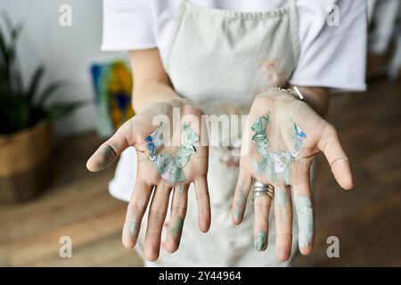 Eine reife Künstlerin mit lackierten Händen verblendet Farben in ihrem Atelier. Stockfoto