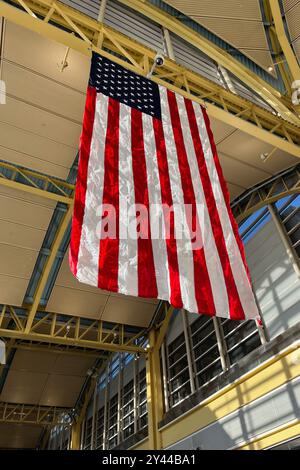 Eine große amerikanische Flagge hängt von der Decke. Die Flagge ist rot, weiß und blau mit einem Stern in der Mitte. Die Flagge hängt an einem Metallbalken. Stockfoto