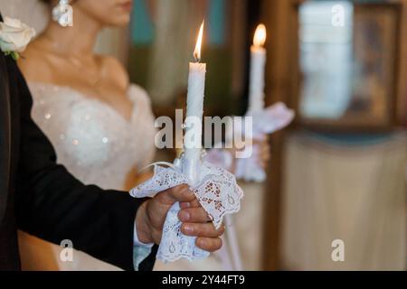 Elegante Hochzeitszeremonie mit Kerzenlicht in einer kirchlichen Umgebung, in der ein Moment der heiligen Vereinigung festgehalten wird. Stockfoto