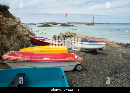 Farbenfrohe Boote am Strand und Phare de l'Ile Vierge, der höchste traditionelle Leuchtturm der Welt 82,5 Meter (271 Fuß) hoch, Bretagne, Frankreich Stockfoto