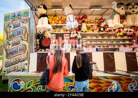 Zwei Mädchen, die am Messestand stehen und einen Spielstand anschauten, um Preise zu sehen Stockfoto