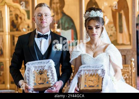 Elegante orthodoxe Hochzeitszeremonie mit Braut und Bräutigam in kunstvoller Kirche. Stockfoto