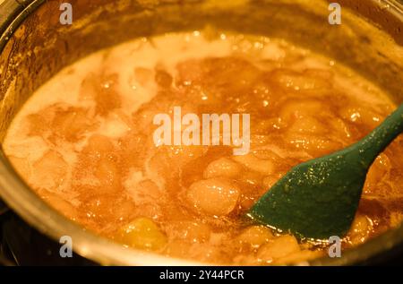 Nahaufnahme der hausgemachten Birnenmarmelade, die in einem Topf gekocht wird, zeigt den Kochvorgang mit einem Teig. Stockfoto