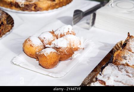 Köstliche Puderzucker-Donut-Kugeln auf Papierteller, mit knusprigem goldbraunem Äußere, verführerischer frittierter Delikatesse und süßem Leckerenkonzept Stockfoto