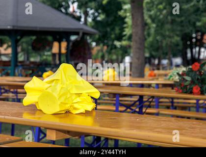 Gelber gefalteter Regenschirm auf hölzerner Picknickbank im öffentlichen Park, Sitzplätze im Freien, Picknickbereich Konzept Stockfoto