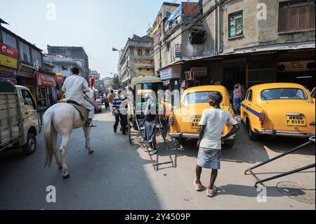 22.02.2011, Kolkata (Kalkutta), Westbengalen, Indien, Asien - alltägliche Straßenszene mit traditionellen gelben Taxis, Rikscha-Puller, Fußgängern und Pferden. Stockfoto