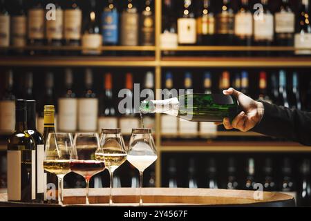 Champagner von Hand in Gläser im Holzkeller gießen, Nahaufnahme Stockfoto