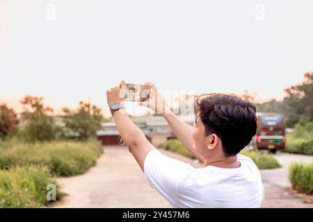 Ein Mann, der Fotos von sich und der Natur in verschiedenen Stilen macht. Der Mann hat den Rücken zur Kamera. An einem sonnigen Nachmittag in der Natur. Ein Mann, der ich Stockfoto