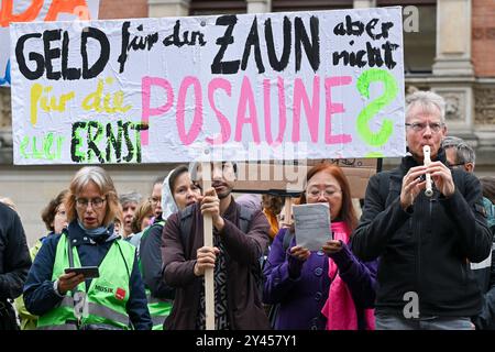 Berlin, Deutschland. September 2024. Musikschullehrer, Schüler und Eltern protestieren vor dem Repräsentantenhaus mit einem Poster mit dem Titel "Geld für den Zaun, aber nicht für die Posaune?". Hintergrund der Demonstration ist ein Urteil des Bundessozialgerichts aus dem Jahr 2022, wonach kostenpflichtige Verträge für regelmäßig beschäftigte Musikschullehrer nicht mehr möglich sind. Quelle: Jens Kalaene/dpa/Alamy Live News Stockfoto