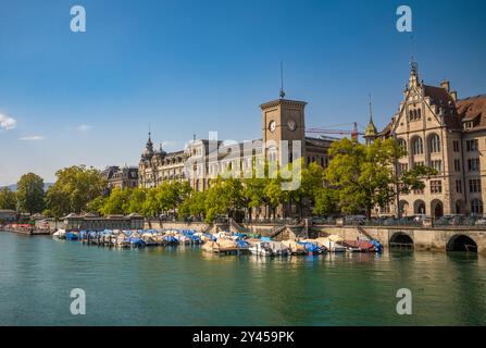 Vergnügungsboote liegen entlang der Stadthausquai und neben großen Gebäuden entlang der Limmat in Zürich, Schweiz Stockfoto