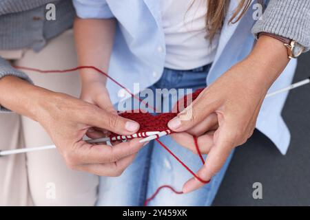 Großmutter bringt ihrer Enkelin das Stricken bei Stockfoto